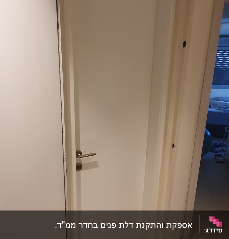דלת לבנה עם ידית מתכת, פתוחה חלקית